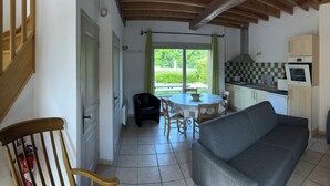 Un escalier mène à un espace repas comprenant une table et des chaises, un canapé et une cuisine équipée d’une cuisinière et de placards.