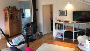 Una sala de estar acogedora con chimenea, muebles de madera, televisor y estantería.