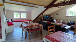 Un dormitorio estilo ático acogedor con cama, televisor, mesa de comedor y sofá.