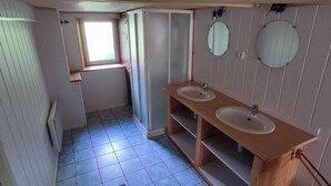 Un baño estrecho con dos lavamanos, una ventana y una puerta que da a otra habitación.