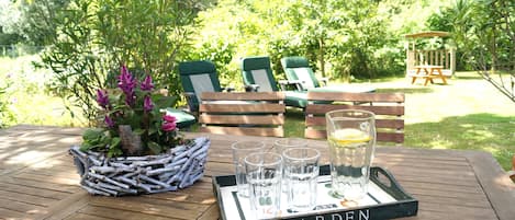 Ein Holztisch mit einer darauf stehenden Tablett, auf dem Gläser und eine Karaffe stehen, und das Tablett ist mit 'GARDEN' beschriftet.