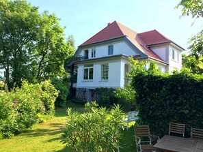 Surrounded by lush greenery, this house offers a serene retreat with a patio area and a small porch.
