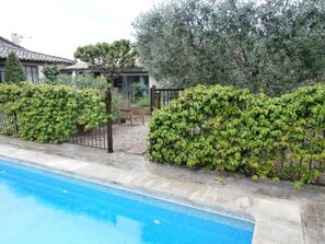 A swimming pool with a tiled edge, surrounded by neatly trimmed hedges and a wooden fence. - charming cottage in the heart of Provence (Saint-Andiol)
