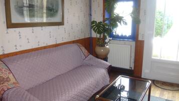 A room with a purple sofa, a glass-top coffee table, a potted plant, and a framed picture on the wall.