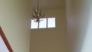 Eine Holztreppe mit Handlauf, einer Deckenleuchte und einem Fenster mit dreifach Verglasung.