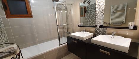 Une salle de bain moderne avec deux lavabos, une douche en verre et un meuble-lavabo avec un miroir.