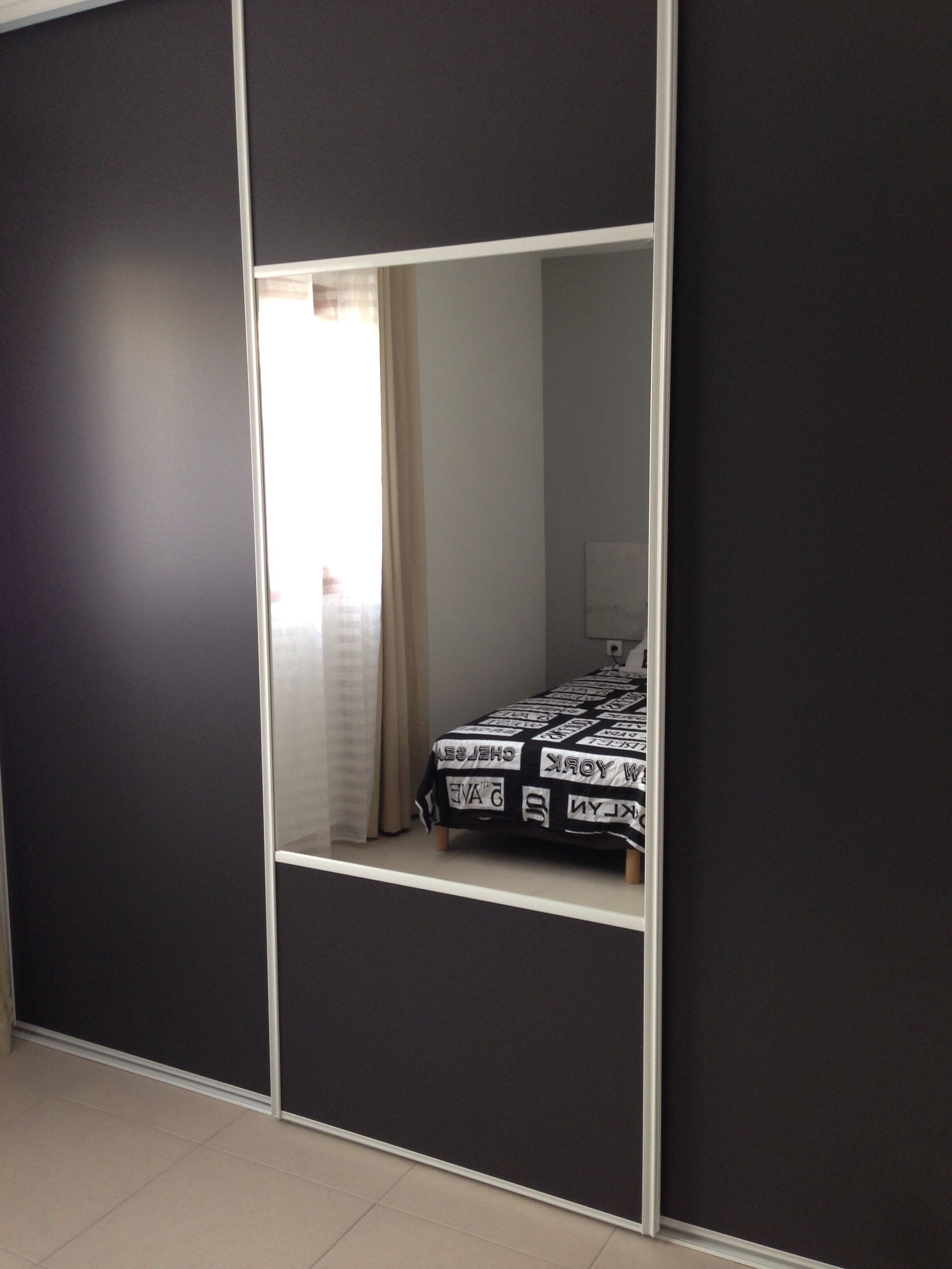 A bedroom with a bed, a wardrobe, and a mirror.