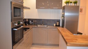 A modern kitchen with stainless steel appliances, wooden countertops, and a built-in sink. - Gîte de la Merluchette  (Nazelles-Négron)