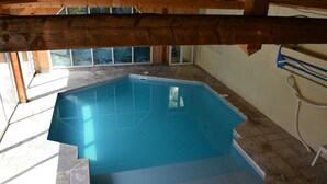 An indoor swimming pool with a tiled floor and a wooden ceiling structure. - Gîte de la Merluchette  (Nazelles-Négron)