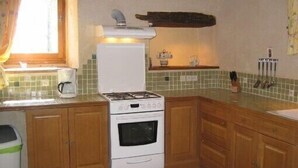 Una cocina con armarios de madera, una estufa blanca y un salpicadero de azulejos.