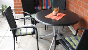 A round table with four chairs, a candle, and a colorful striped curtain in the background. -  Bright and friendly apartment in the center of Grömit (Grömitz)