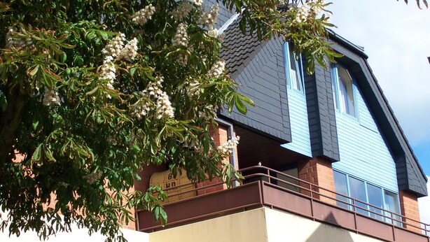 A house with a sloped roof, large windows, and a balcony. -  Bright and friendly apartment in the center of Grömit (Grömitz)