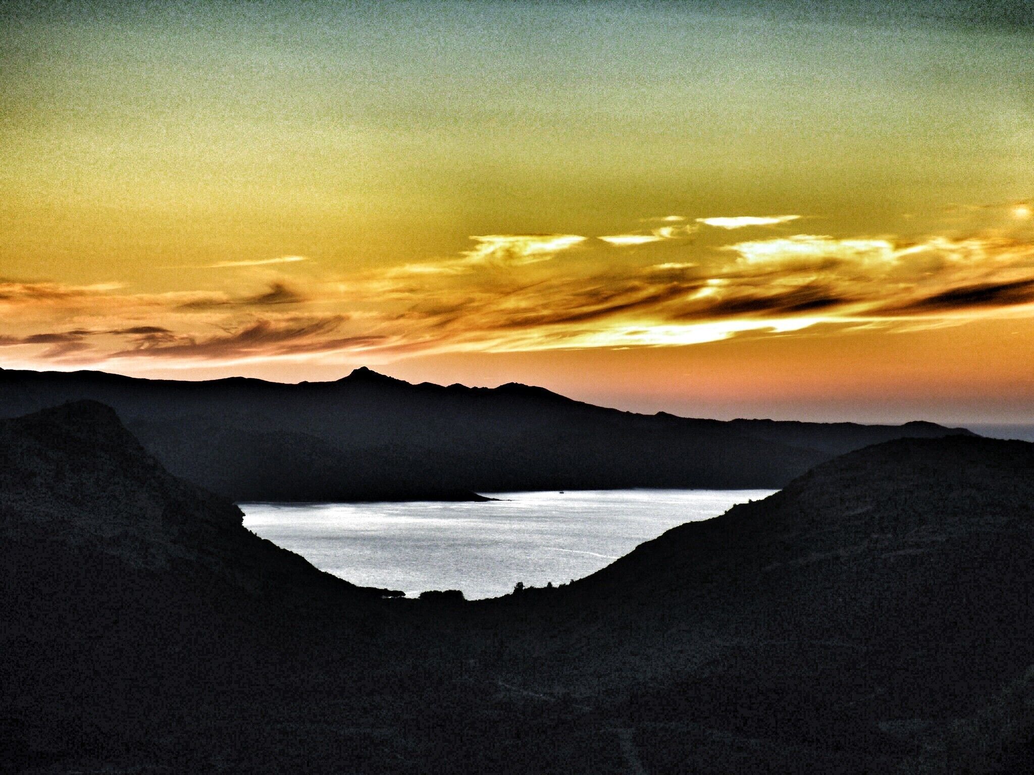 A mountainous landscape with a lake at its base.