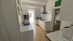 Cozinha com armários brancos, bancada de madeira e painel de azulejos.