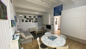 Uma sala de estar acolhedora com um sofá, uma TV e uma mesa de jantar com cadeiras.