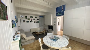 A cozy living room with a sofa, a TV, and a dining table with chairs. - maison st Pierre d'Oléron 4 pers. maxi (Saint-Pierre-d'Oléron)