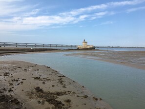 Un paysage côtier avec un phare, un pont et une plage de sable.