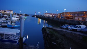 Uma marina com barcos atracados, um cais com carros estacionados e um edifício com placas.