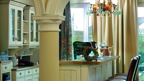 A kitchen with white cabinets, a bar area, and a chandelier.