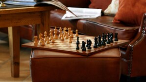 A brown leather armchair with a chessboard in front of it.
