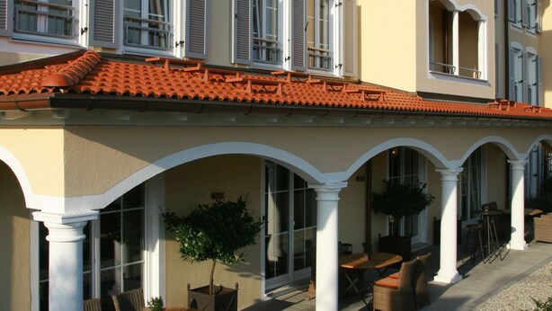 A two-story building with a covered patio area featuring outdoor seating and a potted plant.