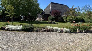 Una casa de techo inclinado, rodeada por un jardín cuidado con diversas plantas y flores.