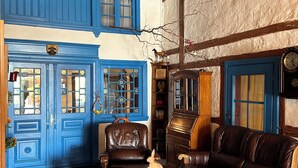 Una habitación con una puerta azul, una mesa de madera y un tapete de bienvenida, además de un sofá de cuero marrón.