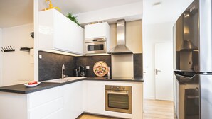 Une cuisine moderne avec des meubles blancs, des appareils en acier inoxydable et un plancher en bois.