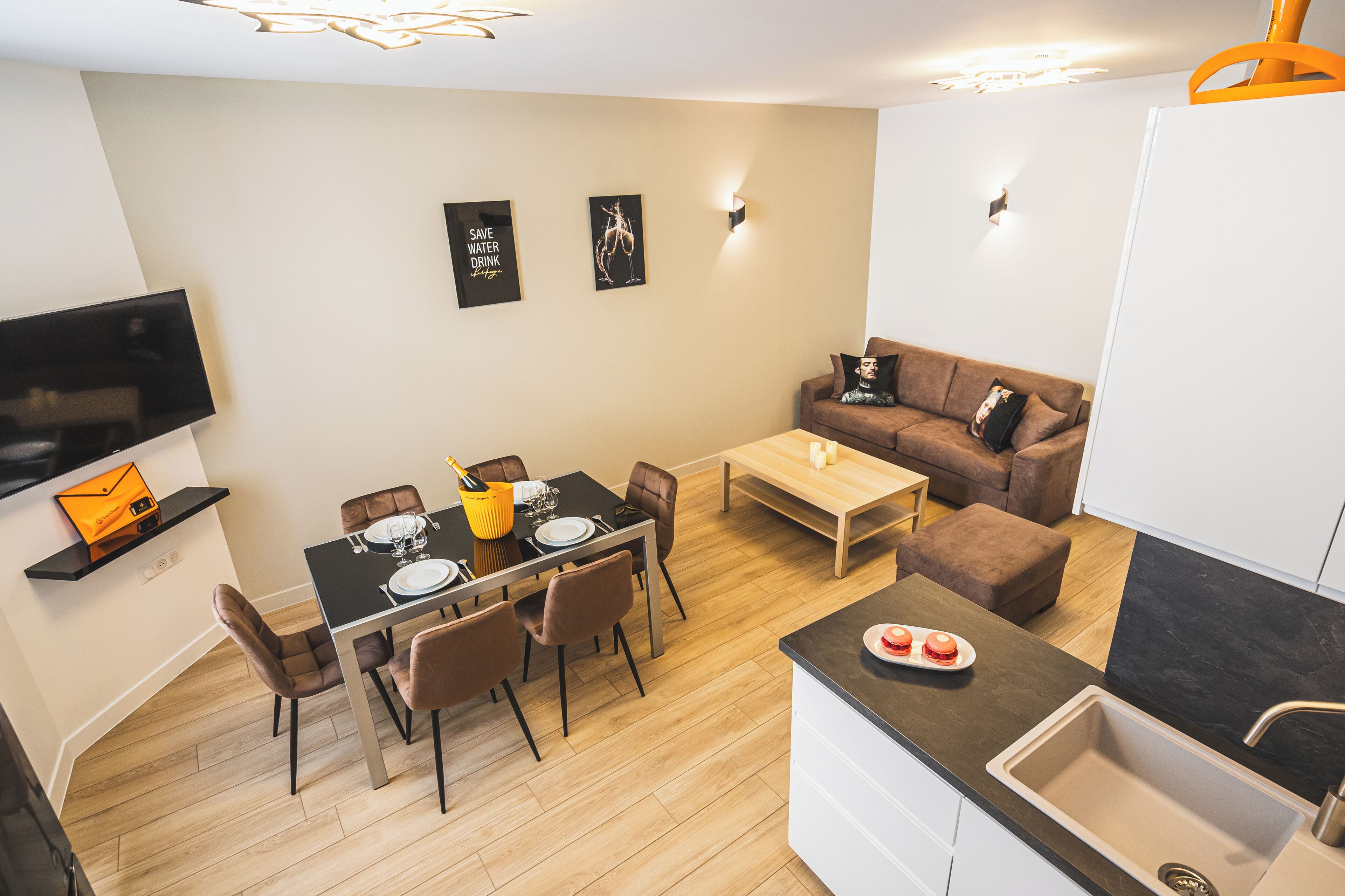 Una cocina moderna con comedor, un sofá y un televisor montado en la pared.