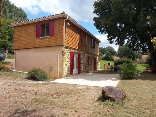 Maison à la campagne, avec de grandes étendues de bois et de champs.
