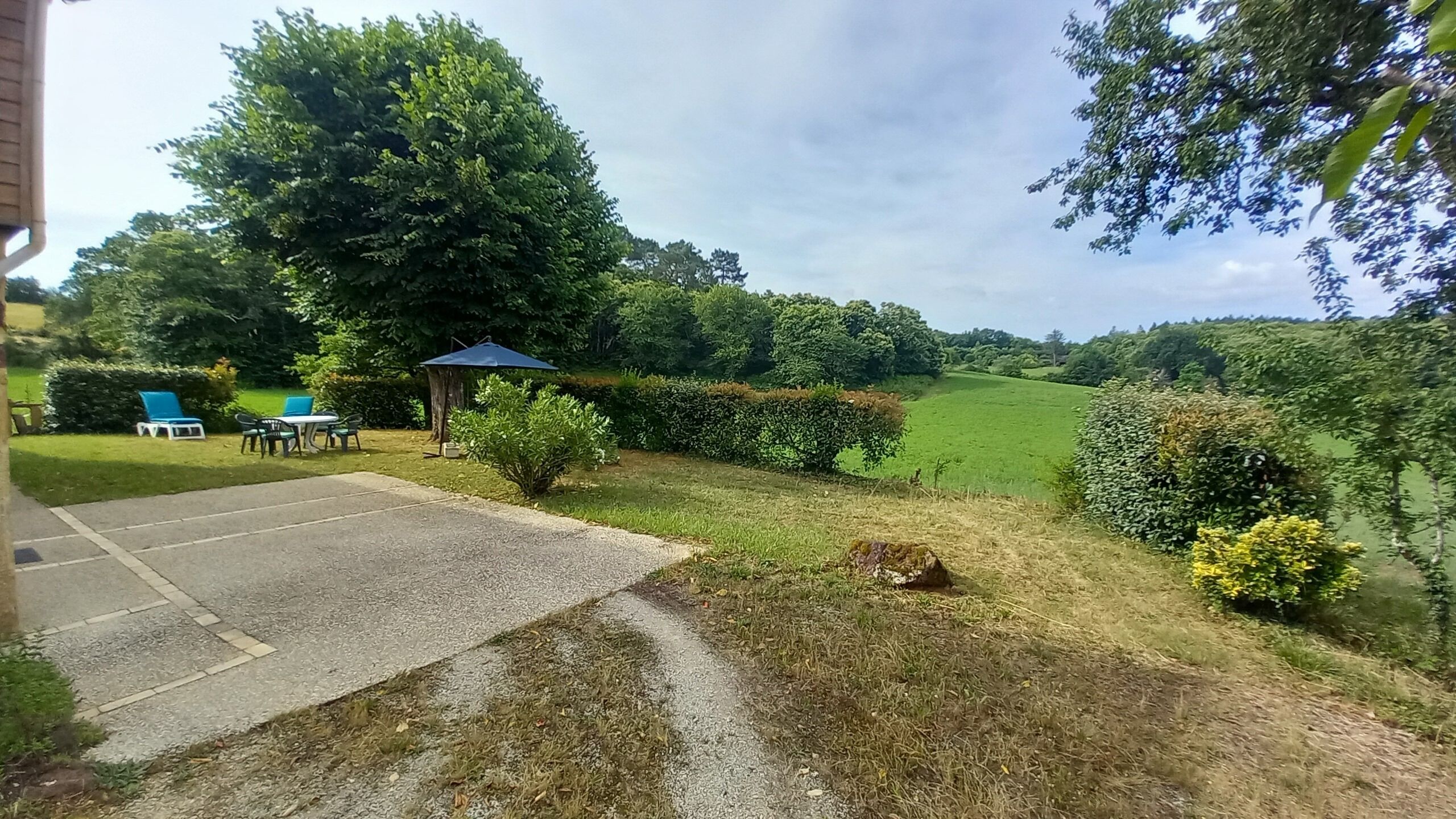 A paved driveway leading to a grassy area with a gazebo and outdoor seating.