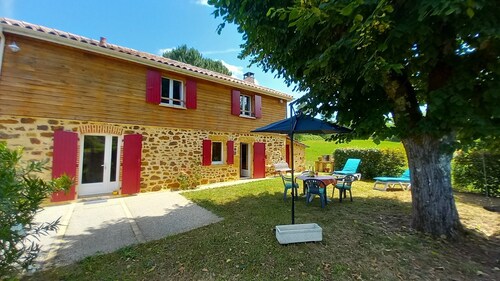 Maison à la campagne, avec de grandes étendues de bois et de champs.