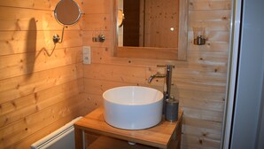 A wooden cabin bathroom with a round mirror, a white sink, and a wooden vanity. - Charming rooms with view  (La Roque-Gageac)