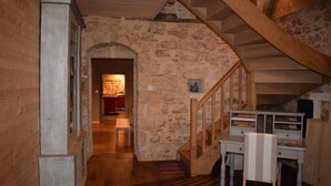A rustic interior with a stone wall, wooden staircase, and a desk with drawers. - Charming rooms with view  (La Roque-Gageac)