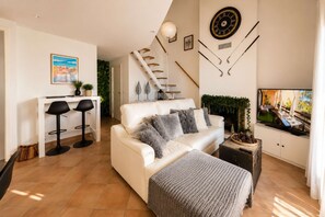 A modern living room with a white sofa, a television, and a fireplace.