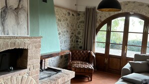 Un interno rustico con camino in pietra, una poltrona in pelle e un divano.