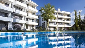 A modern apartment building with a swimming pool in front.