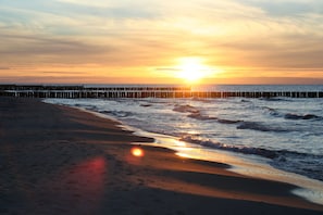 Una playa con un muelle de madera que se adentra en el agua durante el atardecer.