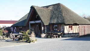 A traditional building with a thatched roof, wooden benches outside, and a sign reading "SKANSCH CHLEBA".