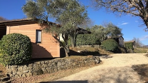 Un bâtiment rustique en bois, doté d’un mur en pierre et d’une allée gravillonnée.