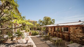 Un espace extérieur aménagé en terrasse, avec des murs en pierre, des chaises vertes et des tables.