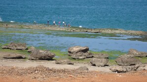 A rocky shoreline with people fishing in the water.