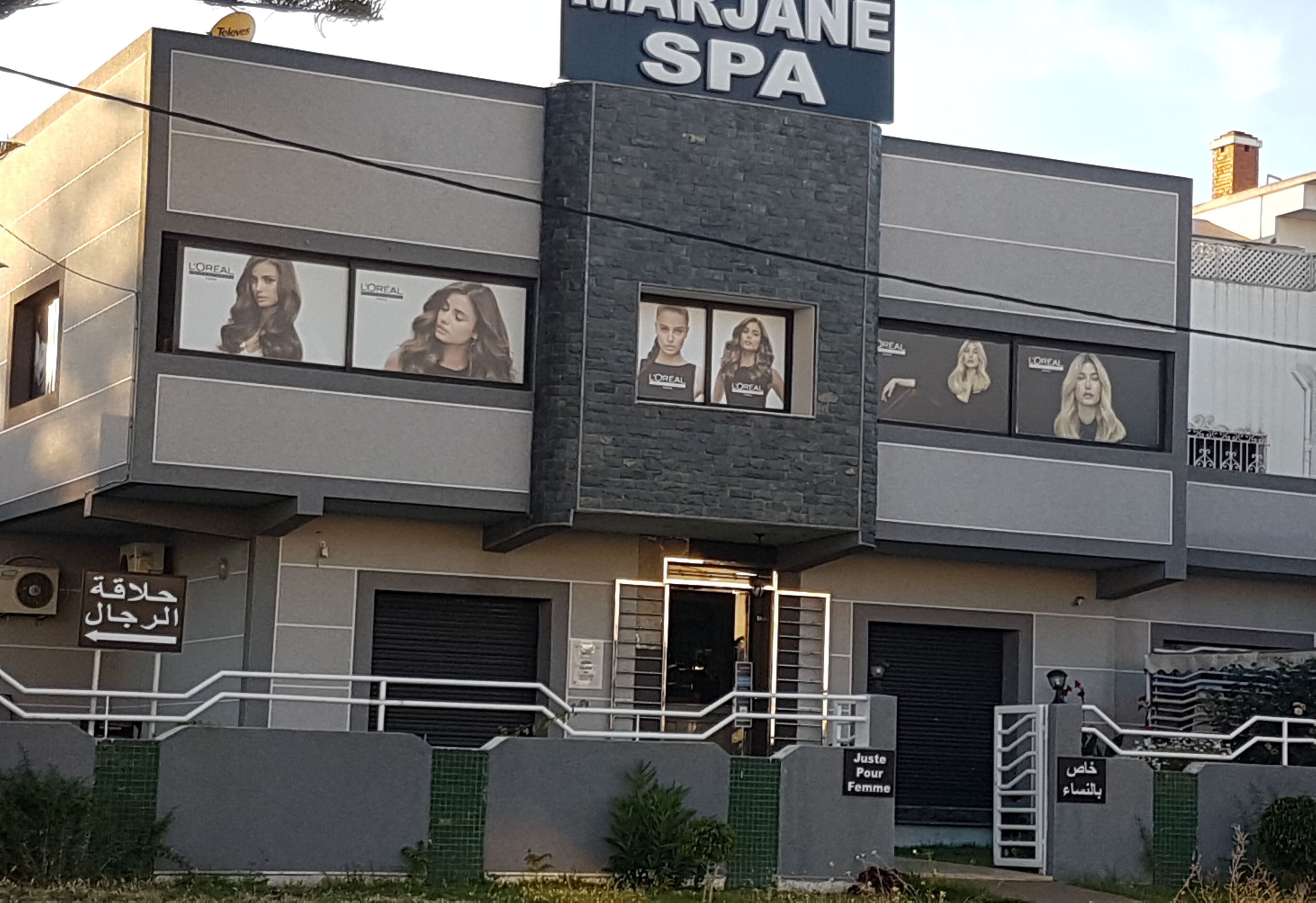 Ein Gebäude mit einem Schild für 'Marjane Spa' und mehreren L'Oréal-Werbeanzeigen.