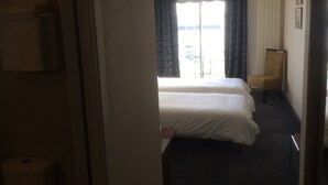 A hotel room with two beds, a chair, a window with curtains, and a view of the outside. -  ENEZ BREHAT, Residence LE PORT, marina, Your balcony on the Port, (Perros-Guirec)