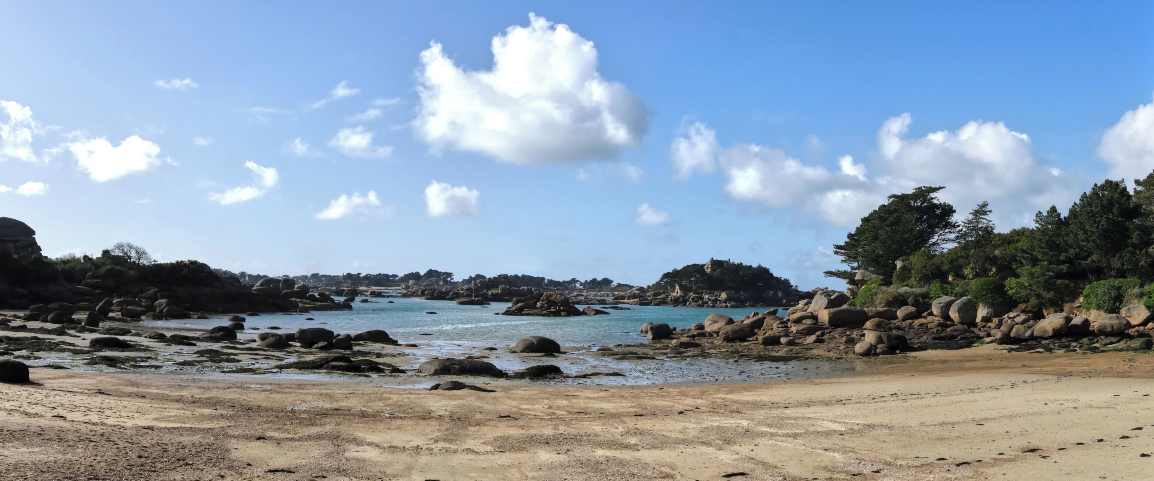 Une plage avec de gros rochers et un ciel dégagé.