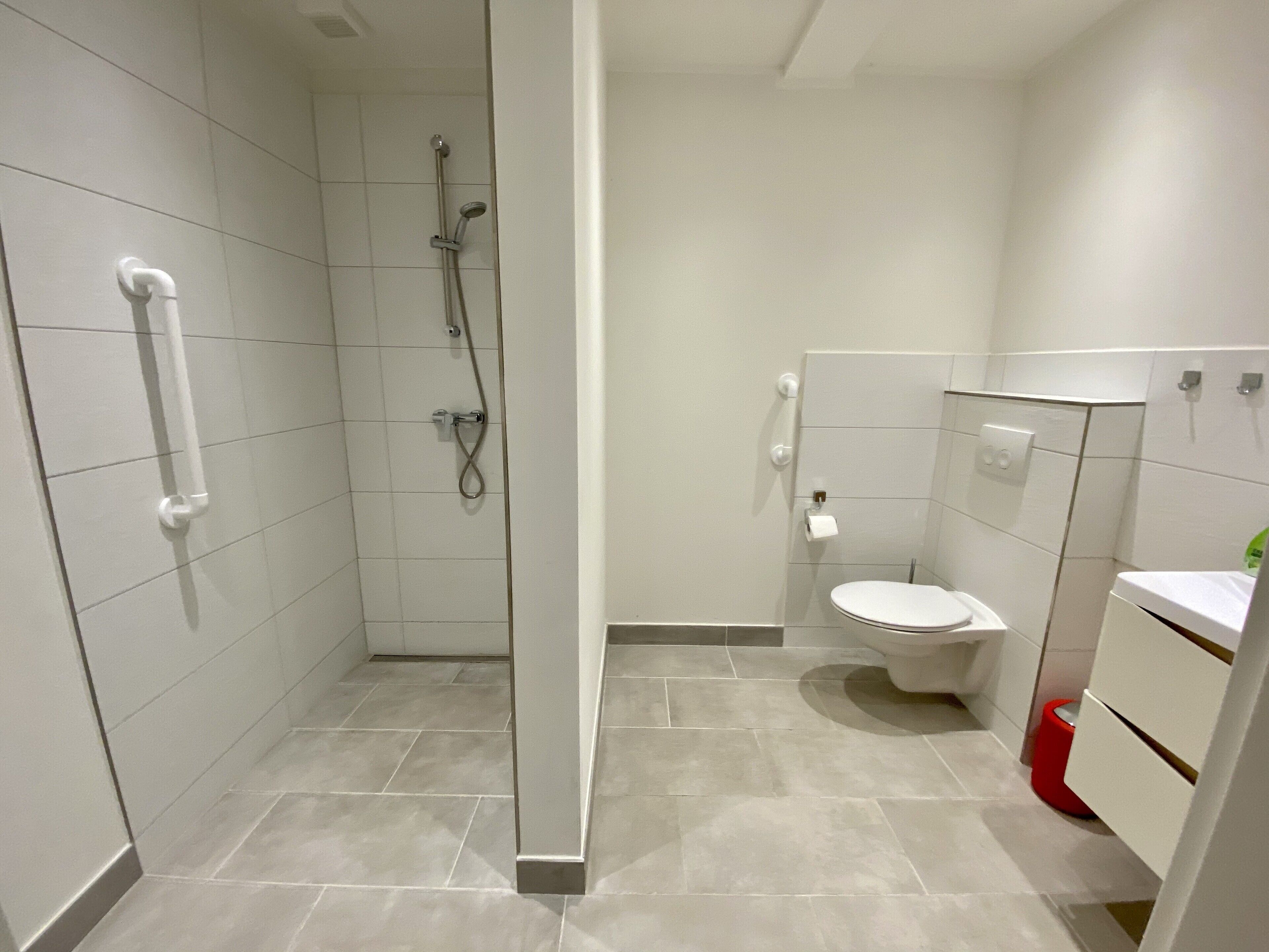 A modern bathroom with a shower, toilet, and storage cabinets.