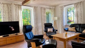 Una sala de estar con televisión, sofás de cuero, una mesa de centro y cortinas.