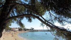 A beach with clear water, people sunbathing, and a tree in the foreground. - wonderful allround view  on S. Tropez bay (Roquebrune-Sur-Argens)