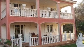 A two-story building with balconies, white railings, and a garden area with a statue. - 100m from downtown and the stores, 300m from the beach and the marina (Porto-Vecchio)