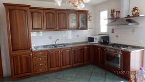 A kitchen with wooden cabinets, a microwave, a stove, and a sink. - 100m from downtown and the stores, 300m from the beach and the marina (Porto-Vecchio)